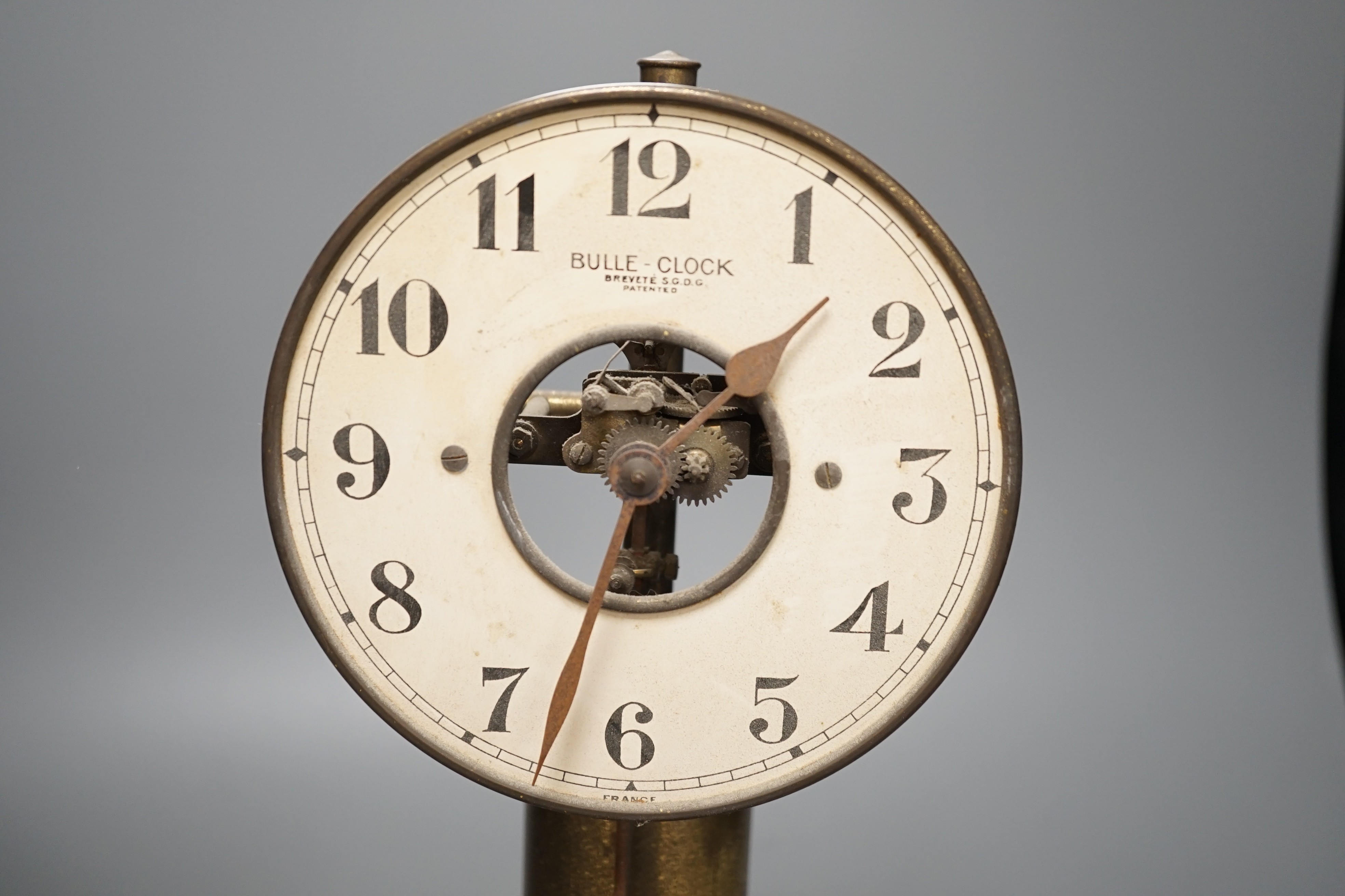 A Bulle electric pendulum clock, with large central brass pillar supporting the 14cm. dial, under a glass dome on a mahogany plinth